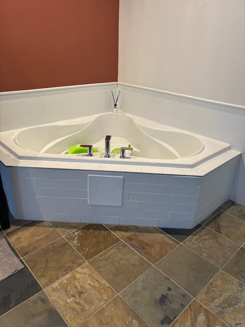 Freshly installed corner bathtub with white subway tile by Active + Green Plumbing